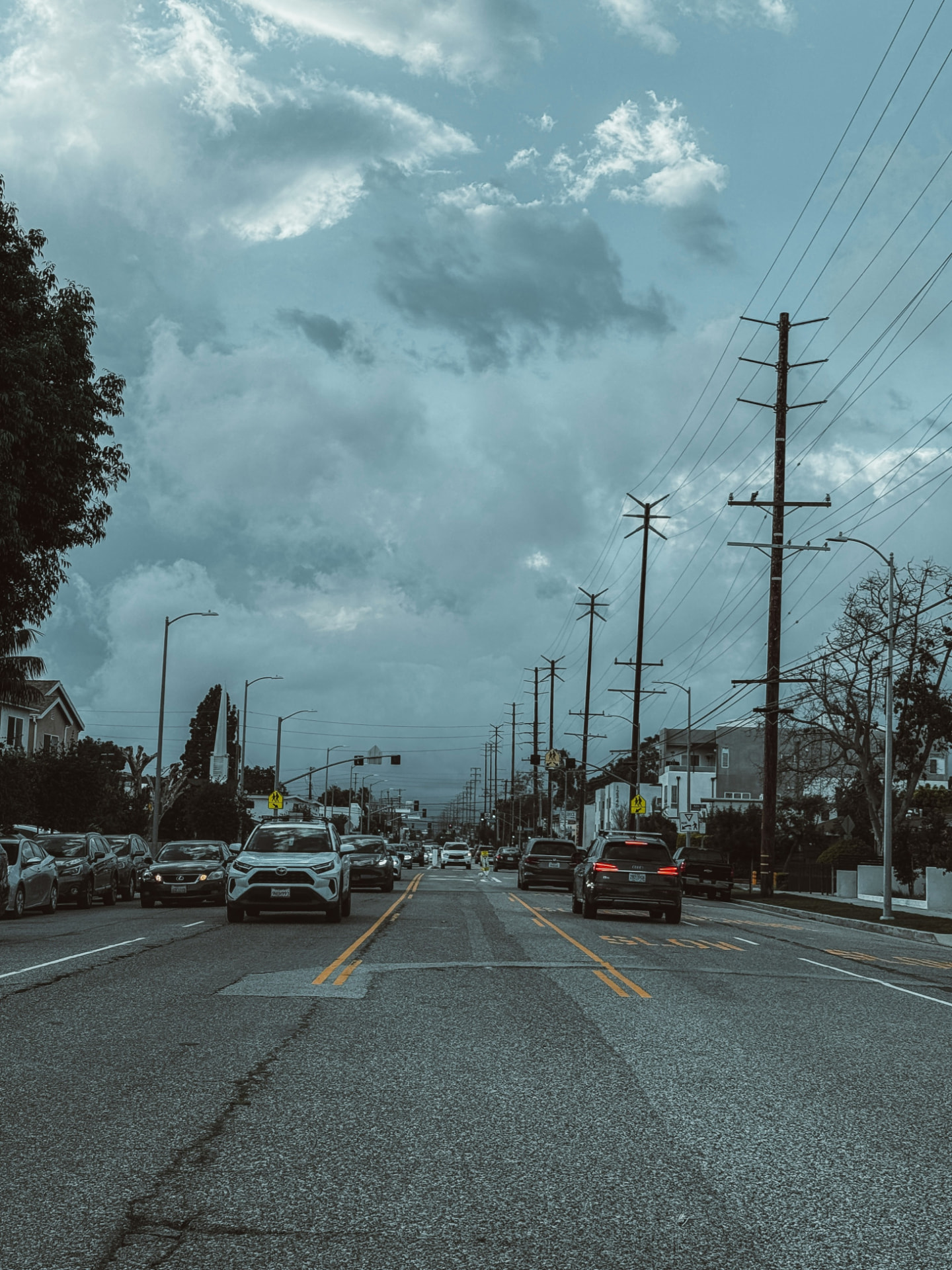 Tree-lined Culver City street with traffic under a dramatic sky