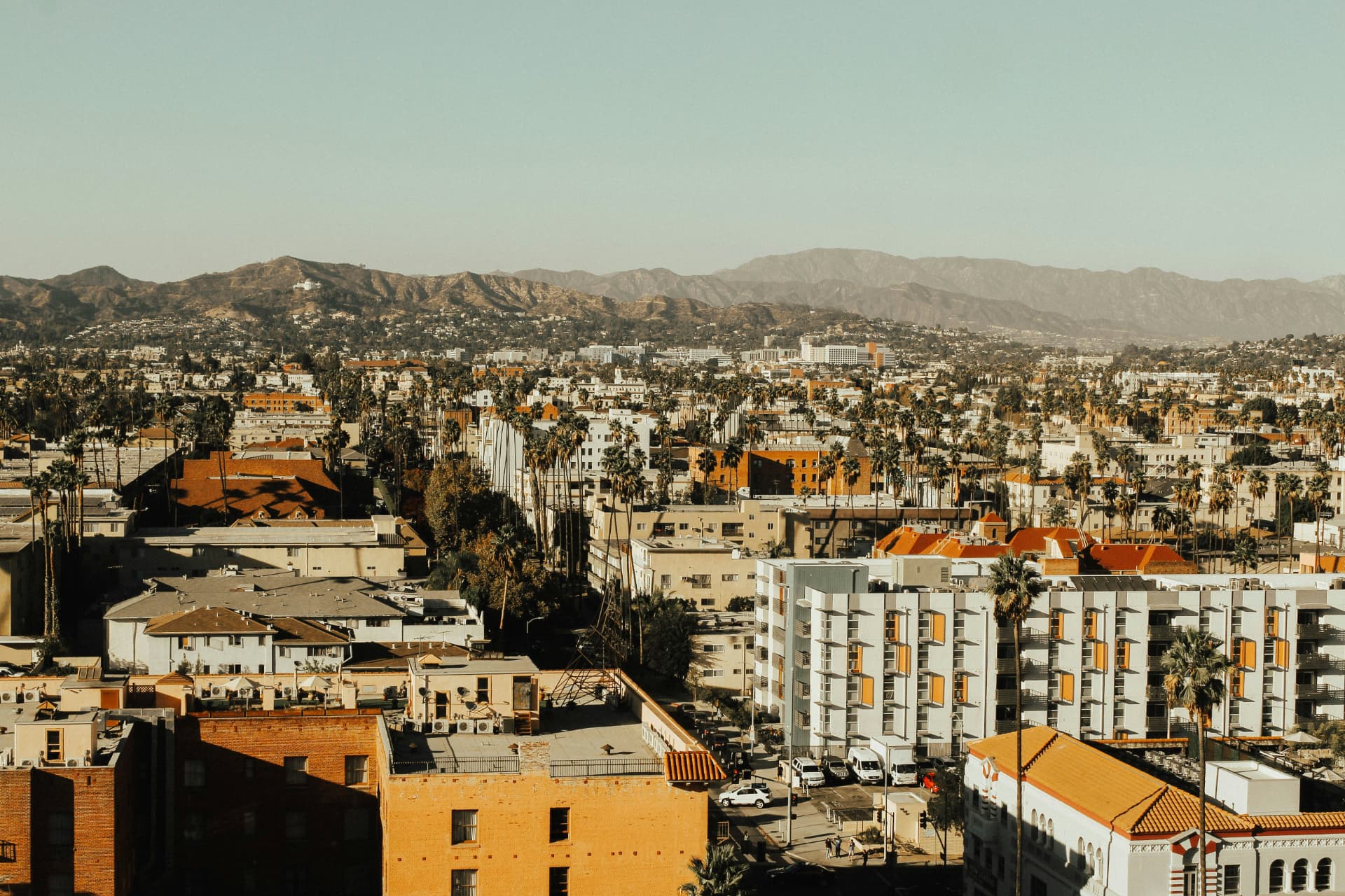 Elevated view over West Los Angeles rooftops, palm trees, and the mountains