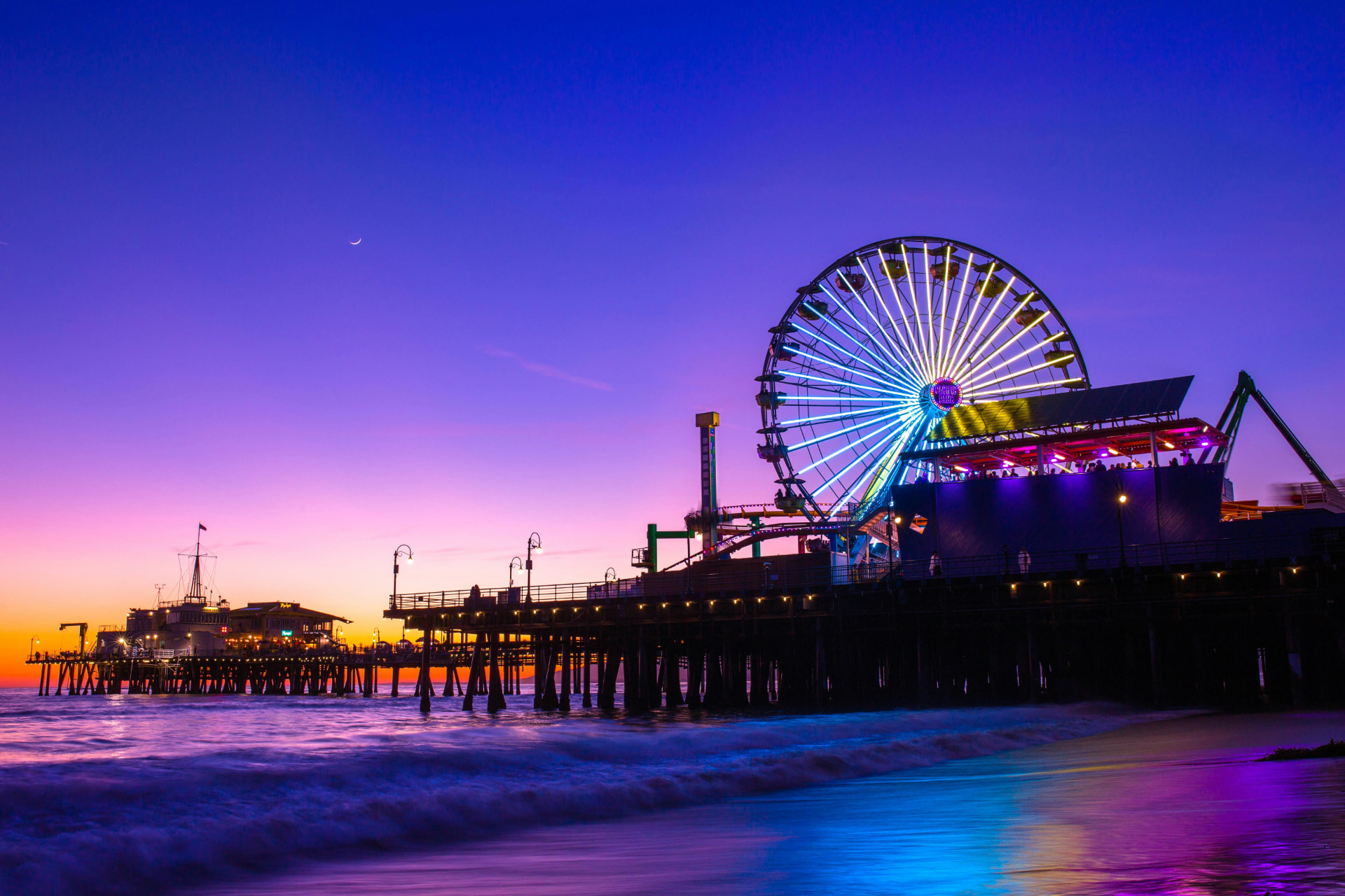 Pacific Park Ferris wheel illuminated at night above the water